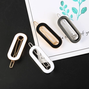 Detail of four geometric oval enamel hair clips in black, white and grey with metal clips