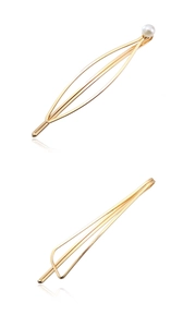 Detailed view of two gold metal geometric hair clips with minimalist pearl accent details
