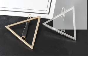 Gros plan de barrettes triangles géométriques minimalistes en finitions or et argent polies