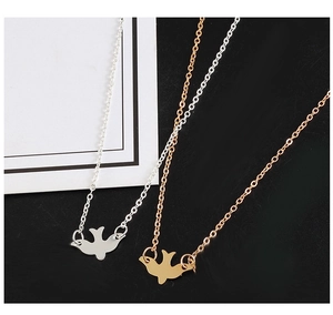 Detailed macro view of minimalist gold and silver flying bird dove pendant necklaces