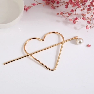 Detail einer minimalistischen goldenen Herz-Haarspange mit Perlen-Haarnadel aus Metall