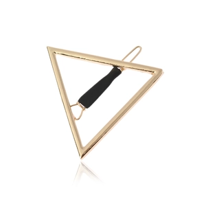 Barrette à cheveux géométrique triangle doré avec grip noir antidérapant sur fond blanc