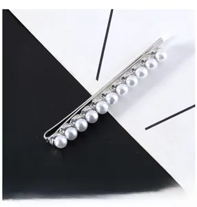 Close-up of 11 white pearls set on a silver metal bar hairpin with a minimalist design