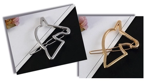Detailed macro view of minimalist hollow horse head metal hair clips in gold and silver