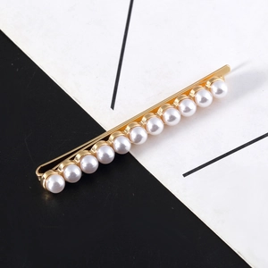 Minimalist gold barrette with eleven white pearls on a modern split background