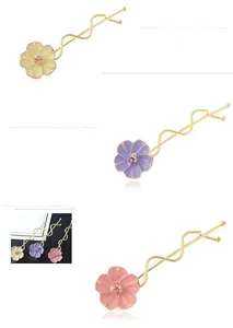 Dettaglio di fermagli per capelli floreali in giallo, viola e rosa con pin dorati ondulati