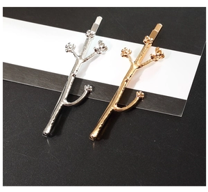 Detailed macro view of gold and silver twig hair clips with textured bark and bud design