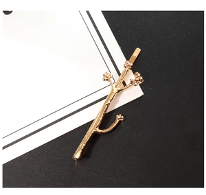 Close-up of golden alloy hair clip with detailed tree branch shape and floral tips