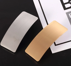 Macro shot of matte gold and silver curved hair clips with brushed metal texture finish