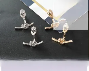 Détail de boucles d'oreilles nœuds minimalistes modernes en finitions or et argent poli