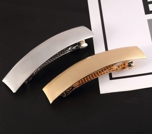 Detail of matte metal spring hair clips in gold and silver with minimalist curved design
