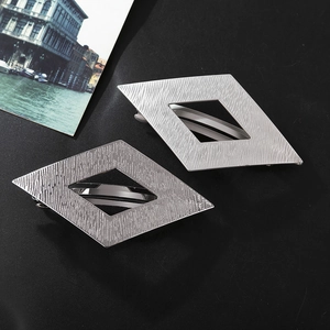 Détail de barrettes géométriques argentées en losange avec une texture en métal brossé