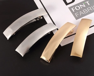 Detailed macro view of matte gold and silver rectangular metal spring hair clips