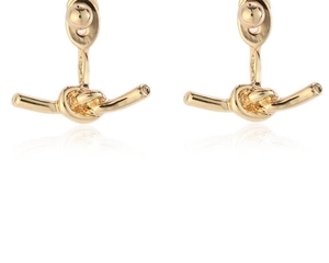 Détail de boucles d'oreilles nœuds dorés avec finition polie sur fond blanc