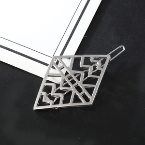 Silver hollow geometric diamond hair clip with intricate line patterns on a dark backdrop