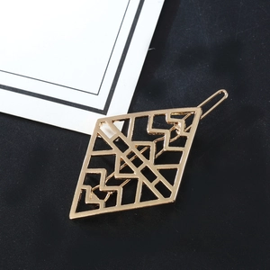Modern hollow rhombus alloy hair clip in golden finish on a dark textured background