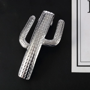 Silver cactus hair clip with wavy metallic texture on a minimalist black background