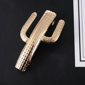 Golden cactus metal hair clip with wavy texture on a black and white background