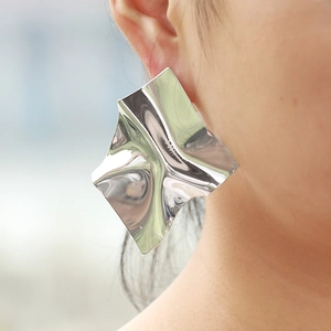Boucles d'oreilles clous géométriques argentées surdimensionnées sur mannequin femme