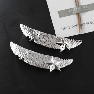 Detail view of silver wing-shaped hair clips with star studs and honeycomb texture