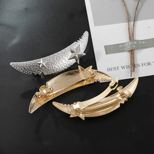 Detail of matte gold and silver moon hair clips with star relief and metal spring back