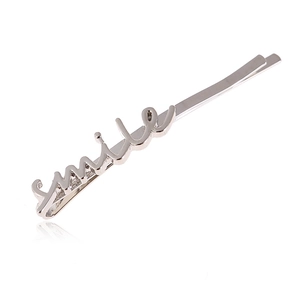 Détail d'une barrette argentée avec un design minimaliste du mot smile en métal