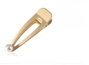 Detail view of a matte gold hollow metal duckbill hair clip with a lustrous white pearl