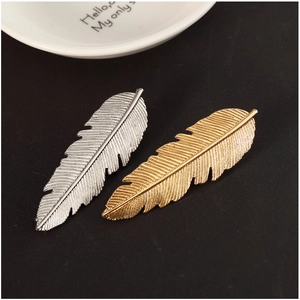 Paire de barrettes à cheveux en forme de feuille, finitions or et argent, sur fond noir