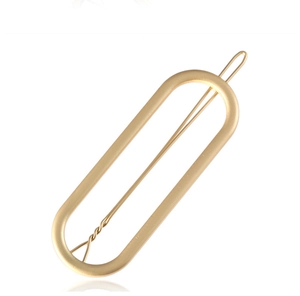 Detailed macro of matte gold hollow oval metal hair clip with minimalist needle pin