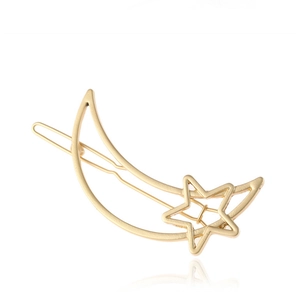 Macro view of a matte gold metal hair clip with minimalist crescent moon and star shapes