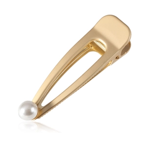 Detailed macro view of matte gold metal hair clip featuring an elegant white pearl accent