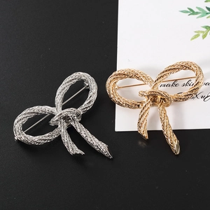 Set di spille a fiocco con trama a corda intrecciata color oro e argento su sfondo moderno