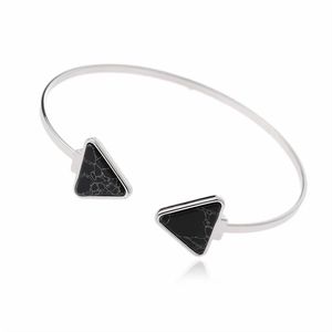 Detailed close-up of C-shaped silver cuff bracelet with two triangular black stones