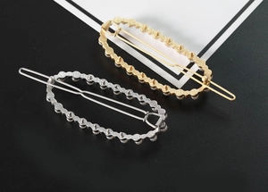Primo piano di eleganti fermagli ovali oro e argento con decorazioni di perle bianche