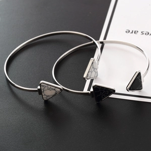 Detail view of two open cuff bracelets featuring marble-textured triangle stone ends