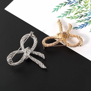 Dettaglio di spille a fiocco oro e argento con una raffinata trama in metallo