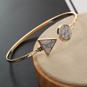Gros plan d'un bracelet doré avec pierres de marbre sur un support en bois