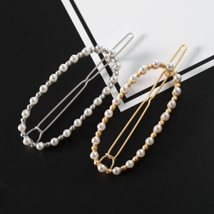 Dettaglio di due fermagli per capelli ovali con perle in finitura oro e argento eleganti
