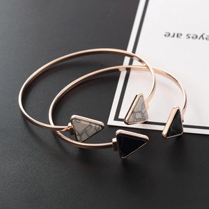 Detail view of rose gold open cuffs featuring black and white triangle marble accents