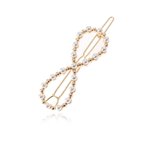 Barrette dorée en forme de huit ornée de perles blanches brillantes sur un fond blanc pur
