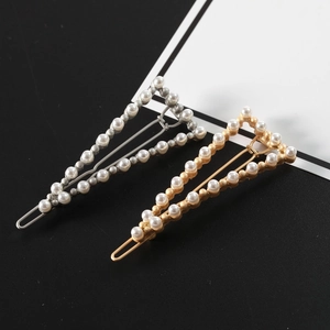 Detail view of gold and silver triangle hair clips with elegant pearl inlay design
