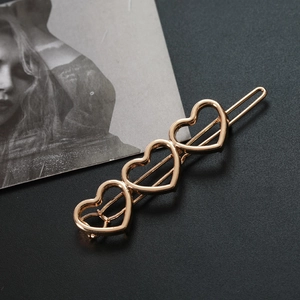 Golden minimalist hair clip featuring three hollow heart shapes with polished finish