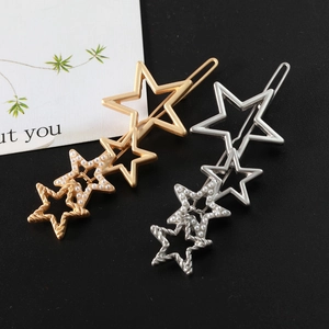 Détail de barrettes étoiles dorées et argentées avec perles blanches sur fond noir