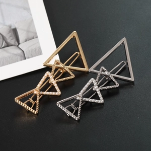 Detail of gold and silver triangle hair clips with white pearl accents and polished finish