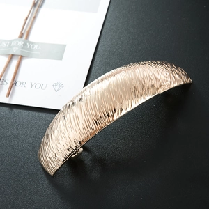 Champagne gold curved metal hair clip with vertical brushed texture and spring closure