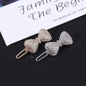 Dettaglio di fermagli per capelli a fiocco con strass brillanti in finitura oro e argento