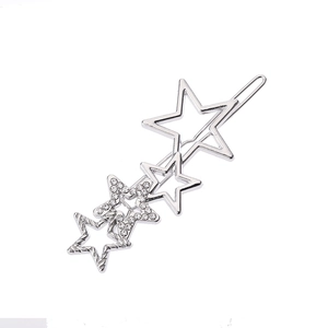Détail de la pince à cheveux étoile argentée avec strass et texture mate sur fond blanc