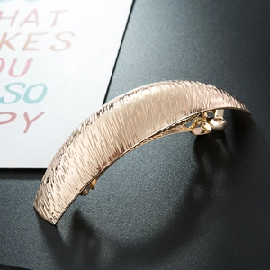 Detailed macro shot of a golden alloy spring hair clip with brushed silk texture