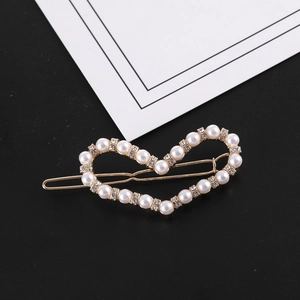 Gros plan d'une pince à cheveux coeur doré avec perles blanches et strass brillants