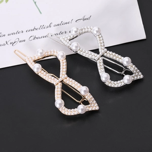 Close-up of elegant gold and silver infinity pearl hair clips on a black background